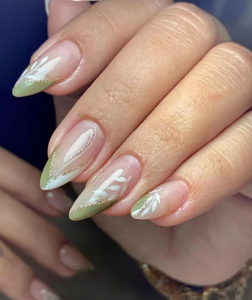 Unhas amendoadas nude com pontas verdes, folhas brancas pintadas e filete dourado