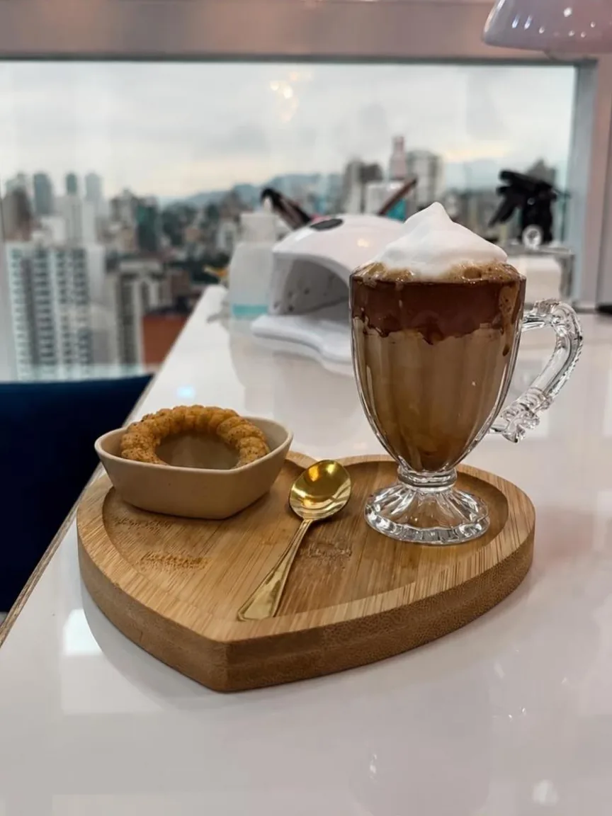 Bebida quente servida em bandeja de madeira na bancada, com vista da cidade
